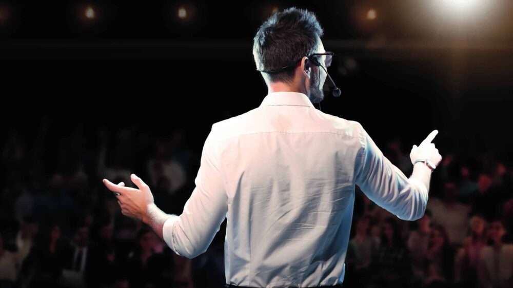 Motivational,Speaker,With,Headset,Performing,On,Stage,,Back,View