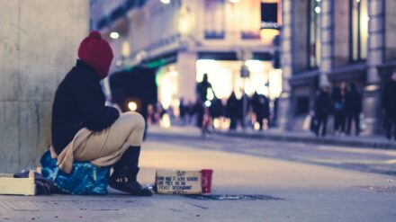 Eine bettelnde Person sitzt an der Straße.